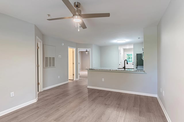 Living room and kitchen area with a ceiling fan and island.
