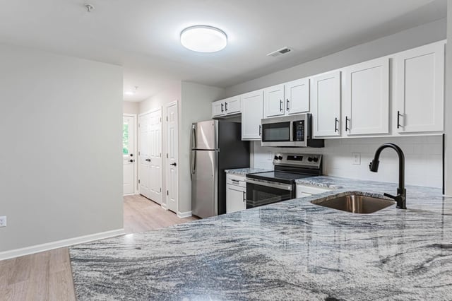 Modern kitchen with white cabinets, granite countertops, and stainless steel appliances.