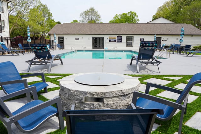Resort-style swimming pool with lounge chairs and a fire pit area.