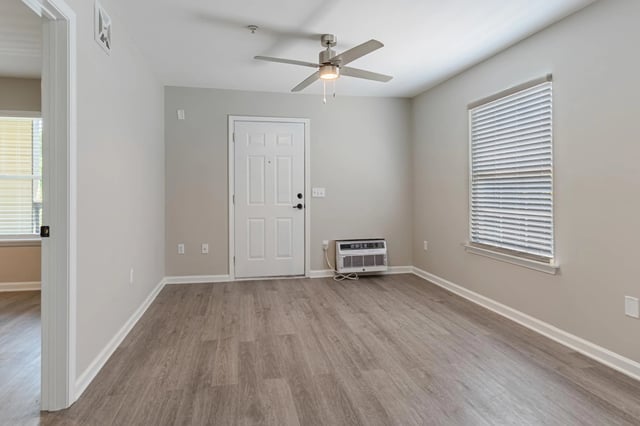 Interior view of an apartment unit showing the entrance door, a ceiling fan, and a window with blinds.