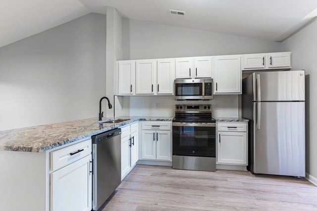 Modern kitchen with stainless steel appliances, white cabinets, and granite countertops.