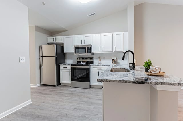 Modern kitchen with stainless steel appliances, granite countertops, and white cabinets.