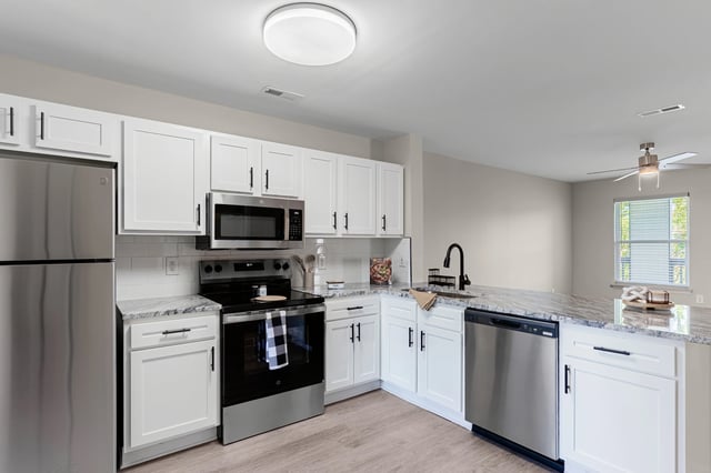 Modern kitchen with stainless steel appliances, white cabinets, and granite countertops.