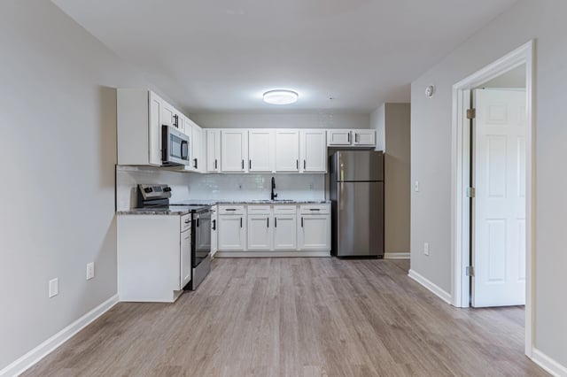 Modern kitchen with white cabinets, stainless steel appliances, and granite countertops.