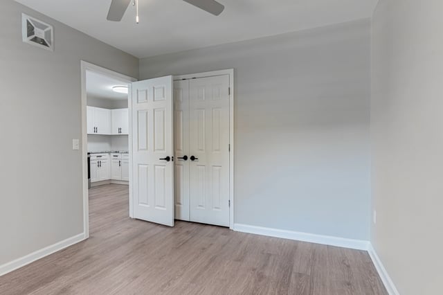 Interior view of a bedroom with double doors and a glimpse of the kitchen through an open doorway.