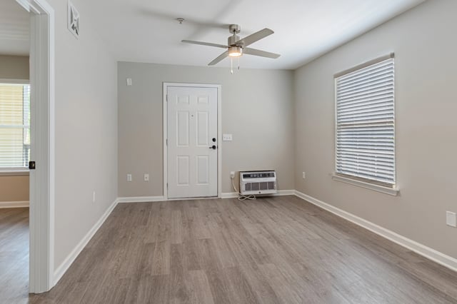 Empty apartment living room with wood-look flooring, ceiling fan, and window.