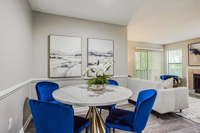 Dining area with a marble table and four blue velvet chairs.