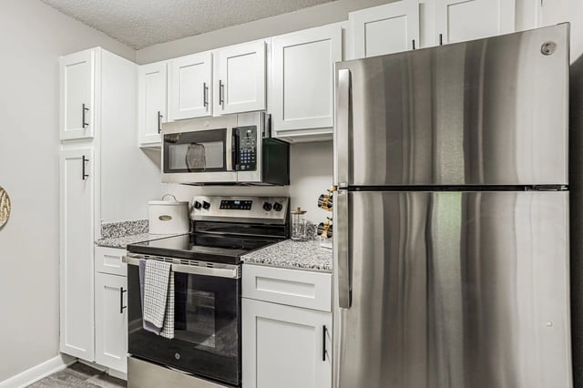 Modern kitchen with stainless steel appliances and white cabinetry.