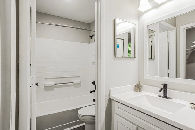 Modern bathroom with a white vanity, black faucet, and a bathtub with a shower.
