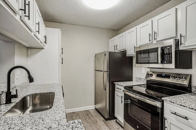 Modern kitchen with granite countertops, stainless steel appliances, and white cabinetry.