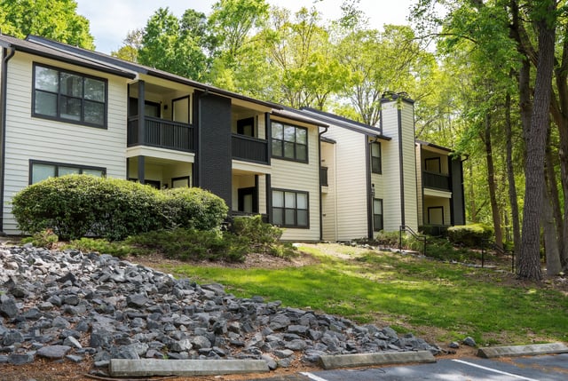 Exterior view of apartment buildings surrounded by lush green trees and landscaping.