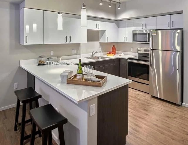 Modern kitchen with stainless steel appliances, white cabinets, and a breakfast bar.