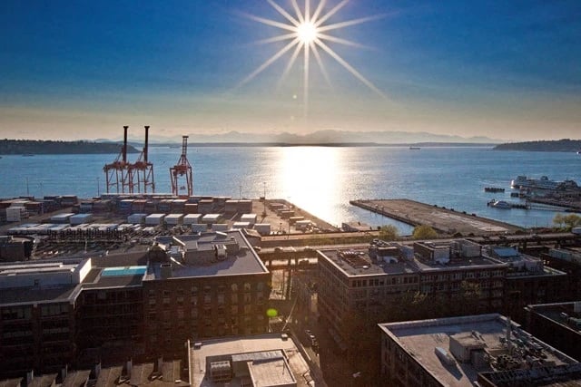 Aerial view of a waterfront community with a sunburst in the sky and a port in the background.