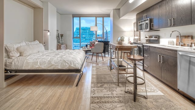 Studio apartment with a Murphy bed, modern kitchen, and city views.