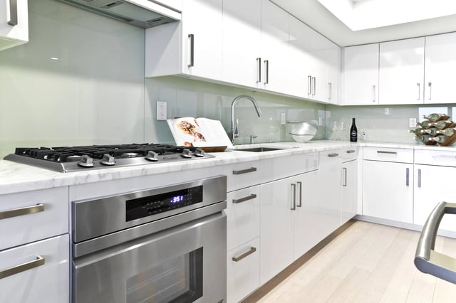 Modern kitchen with white cabinets, stainless steel appliances, and marble countertops.