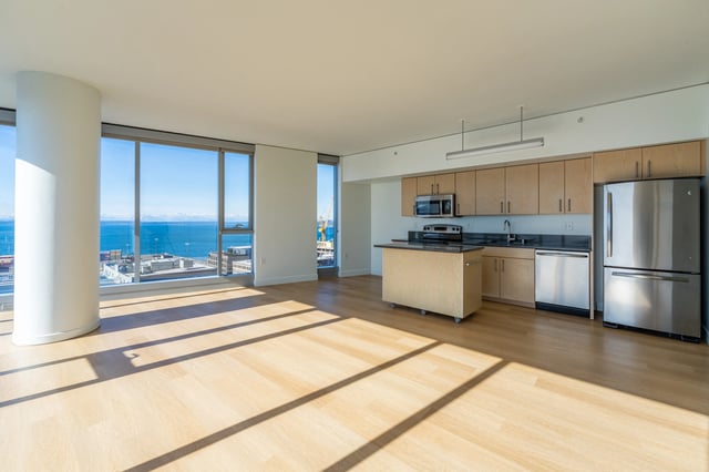 Modern open-concept apartment kitchen with stainless steel appliances and water views.