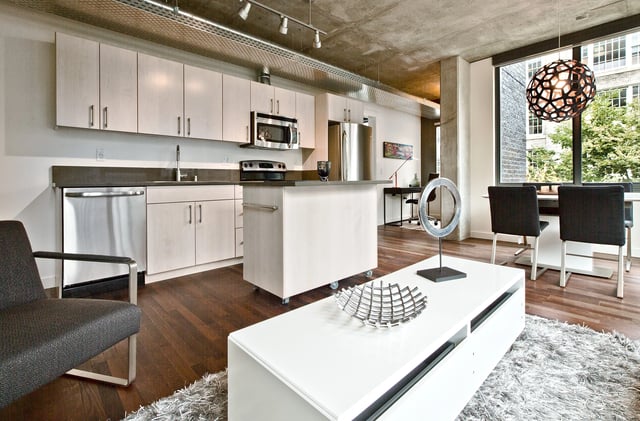 Modern apartment kitchen and living area with island and dining table.