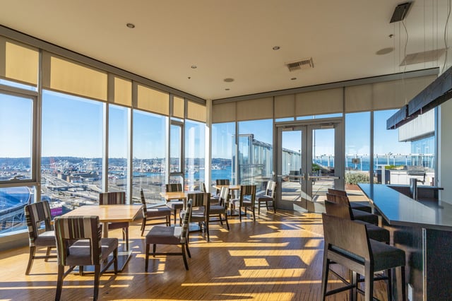 Community lounge with seating and a bar overlooking the city and harbor.