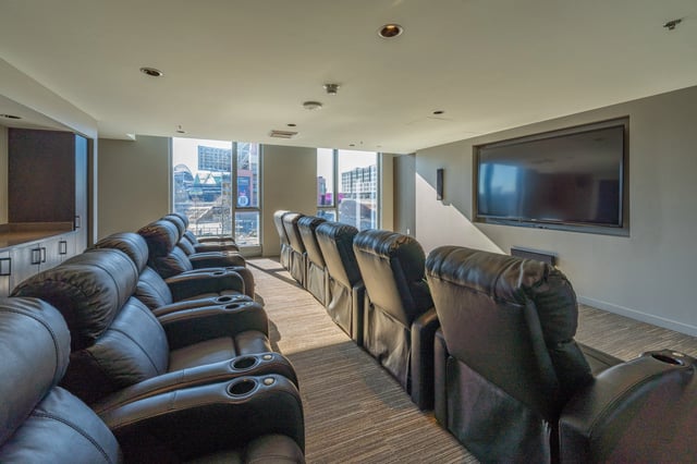 Luxury theater room with plush reclining seats and a large screen.