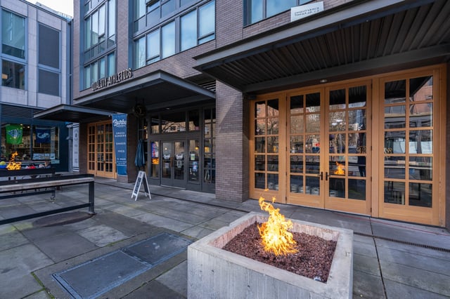 Exterior building entrance with a fire pit and seating area.