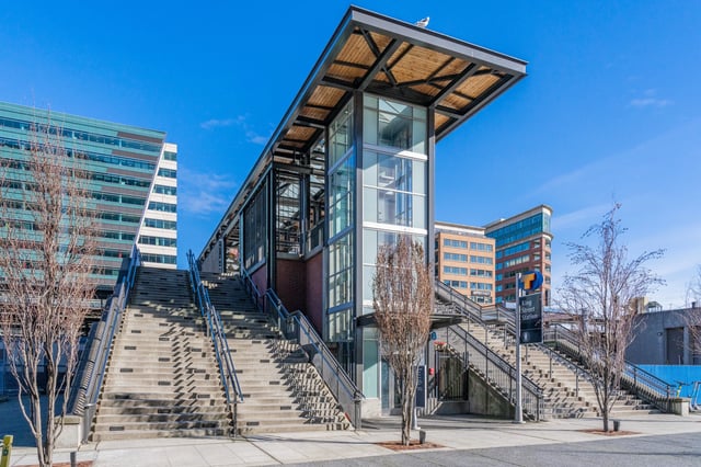 Exterior view of the King Street Station with large concrete staircases and a modern glass and steel elevator structure.