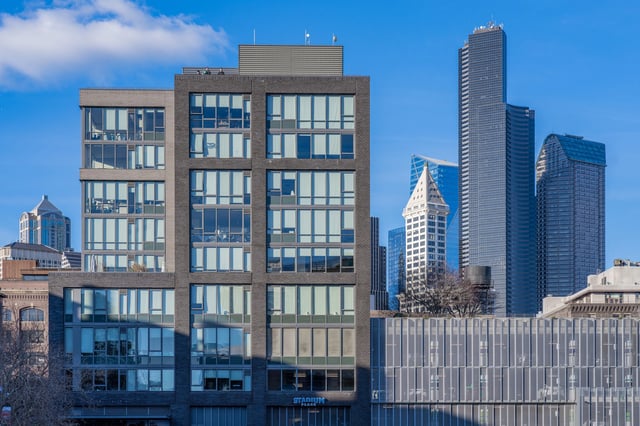 Modern apartment building exterior with large windows and city skyline in the background.