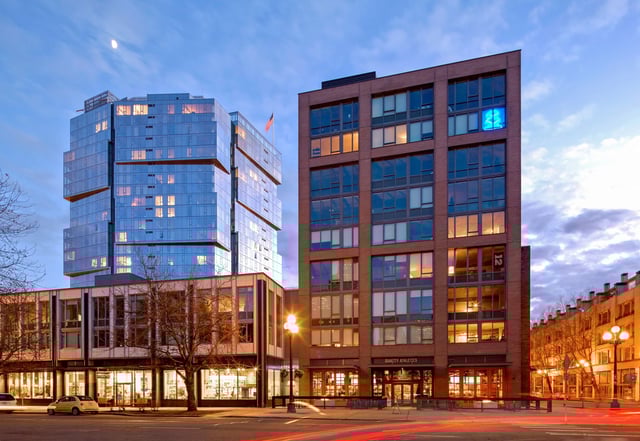 Modern apartment buildings with glass and brick facades at dusk.