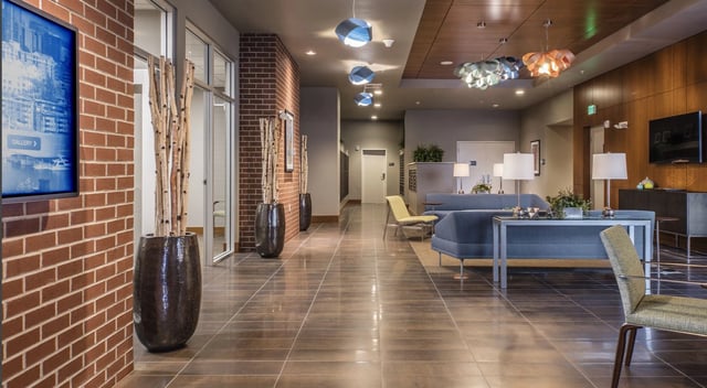 Modern lobby with brick accent wall, abstract pendant lights, and comfortable seating area.
