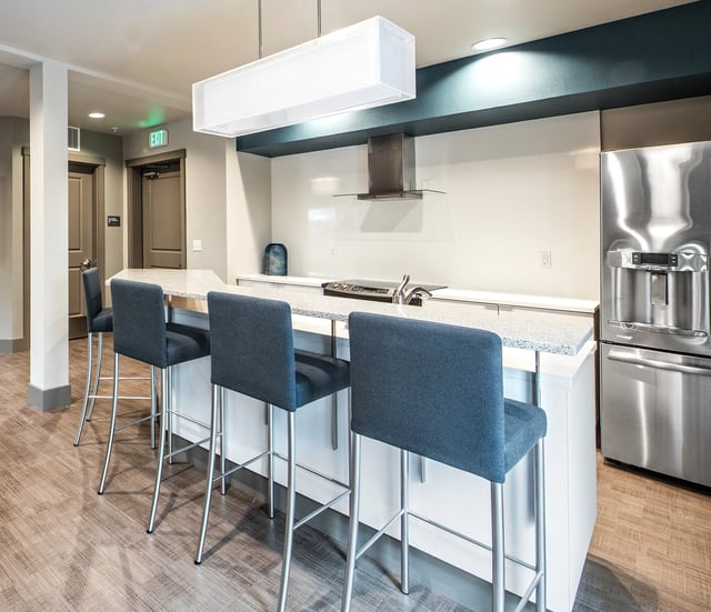 Modern kitchen island with blue bar stools and stainless steel appliances.