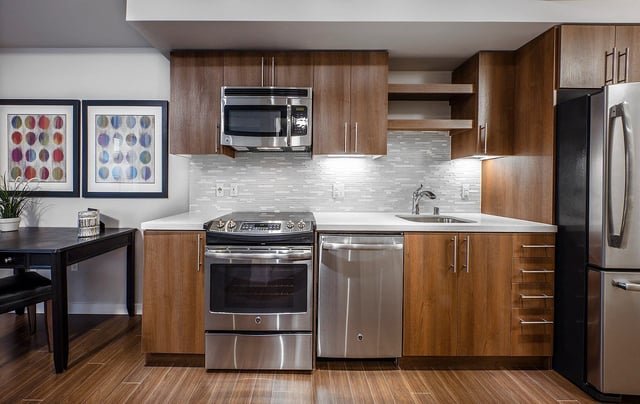 Modern kitchen with stainless steel appliances, wood cabinets, and a dining area.