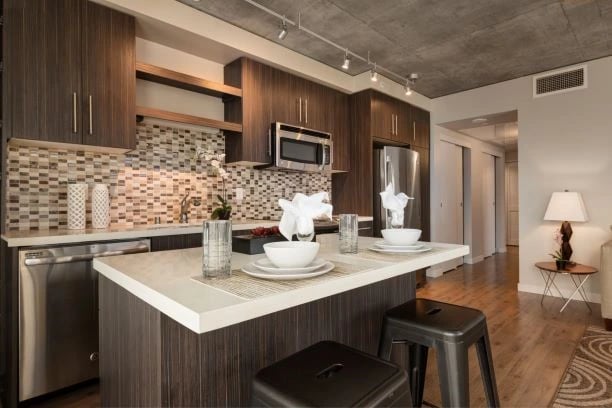 Modern kitchen with dark wood cabinets, granite countertops, stainless steel appliances, and an island with seating.