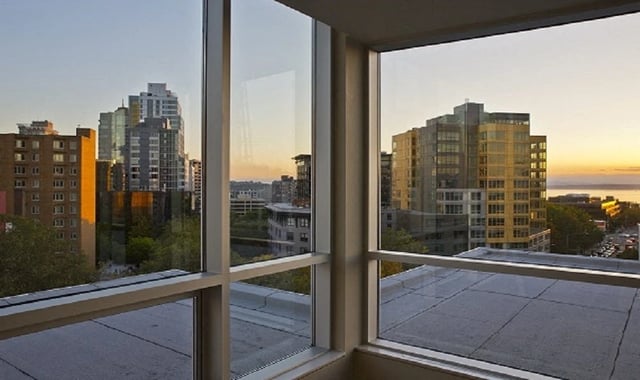 View of city skyline and water at sunset from a balcony.