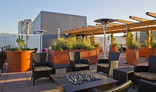 Rooftop patio with fire pit, seating, and planters.