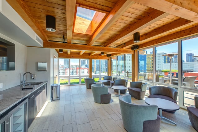 Modern lounge area with city views, featuring comfortable seating and a kitchenette.