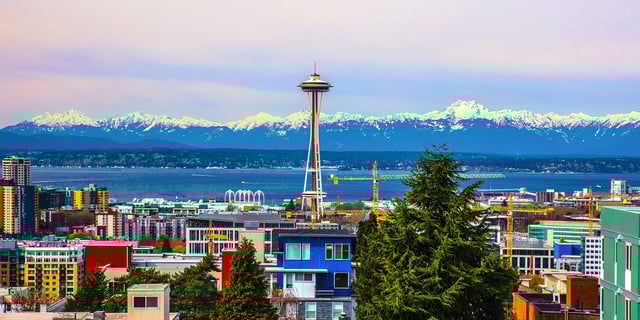 View of Seattle skyline with Space Needle and snow-capped mountains in background.