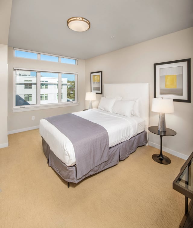 Bedroom with a king size bed, bedside tables, and a window overlooking the city.