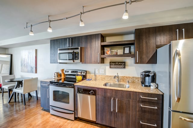 Modern kitchen with stainless steel appliances, granite countertops, and dark wood cabinetry.