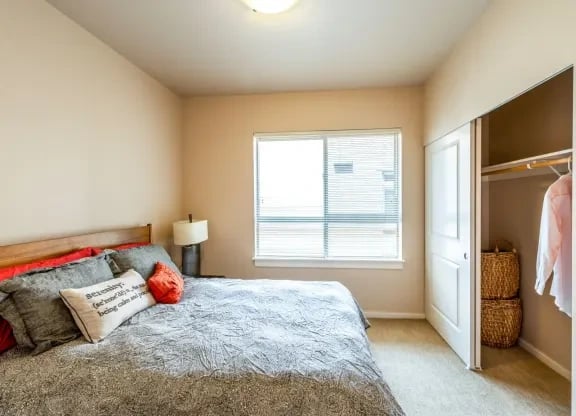 Bedroom with a large bed, pillows, nightstand, window, and an open closet.