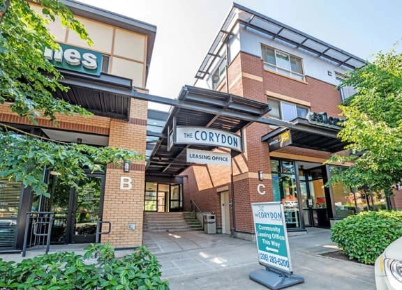 Exterior view of a multifamily community entrance with leasing office signage and brick buildings.