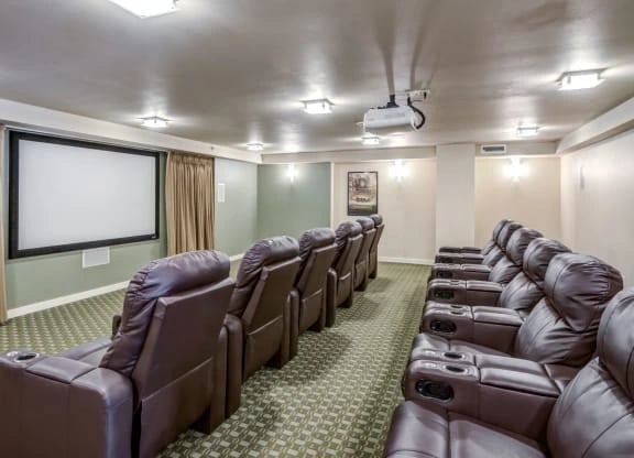Indoor resident theater with multiple brown leather recliners and a projector screen.