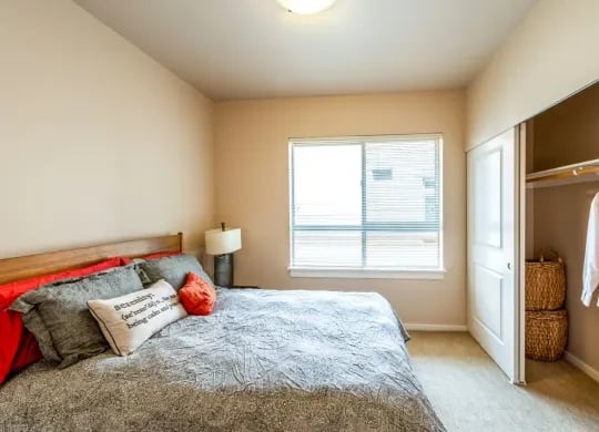 Bedroom with a bed, nightstand, window, and open closet showing baskets.