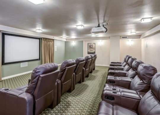 Community theater room with rows of brown leather recliners and a projection screen.