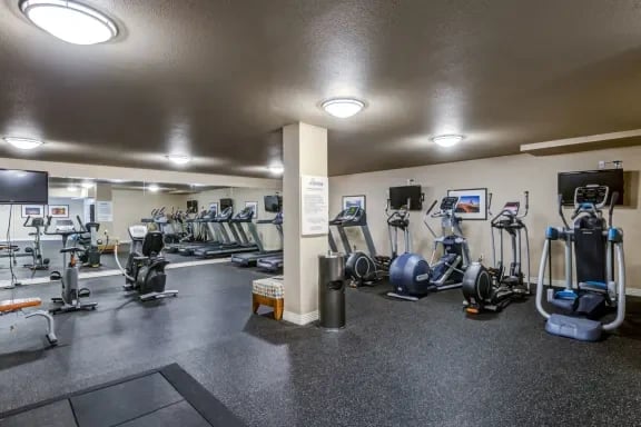 Fitness center with cardio machines and weights in a residential building.