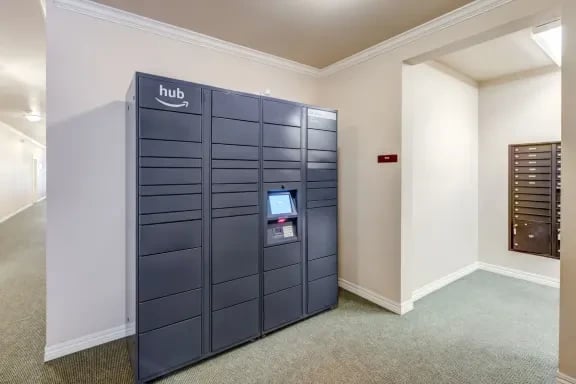 Row of dark gray parcel lockers in a hallway of an apartment building.
