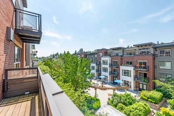 Balcony viewpoint overlooking a landscaped communal courtyard with seating and surrounding apartment buildings.