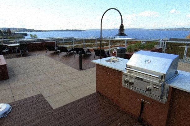 Rooftop grilling station with a built-in grill and sink, overlooking a body of water.