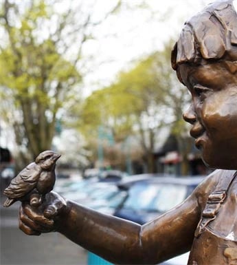Bronze statue of a child holding a bird