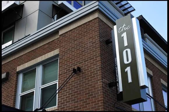 The 101 Luxury Apartment Living sign on a brick building exterior.