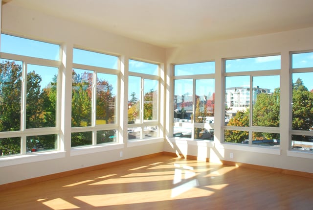 Empty living room with large windows overlooking a park in autumn.