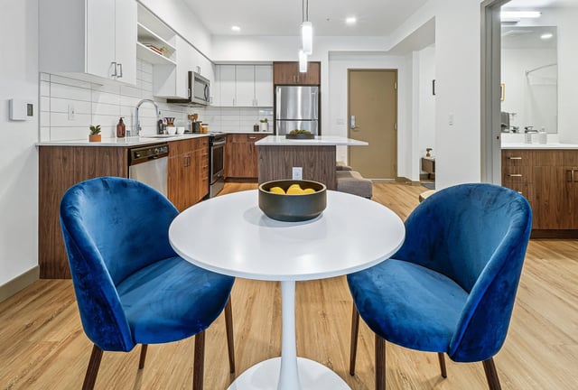 Kitchen and dining area with blue chairs and a white table.